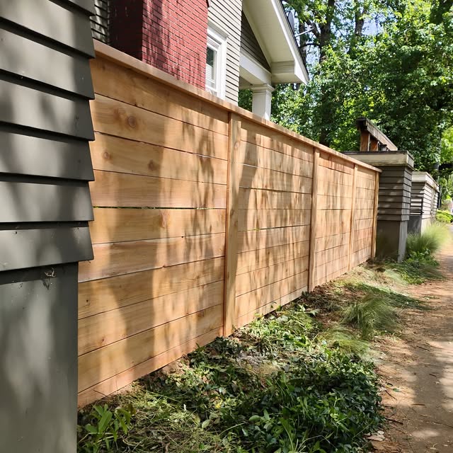 Modern cedar horizontal fence next to a brick home